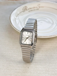 Detail of silver square stainless steel watch with retro elastic metal strap on a white plate