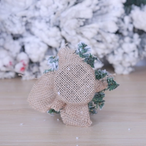 Mini artificial Christmas tree with snowy branches and rustic burlap base for tabletop decor
