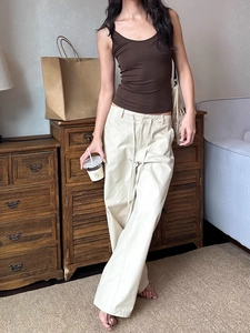 Women's vintage cream drawstring wide-leg pants and brown tank top in a home setting
