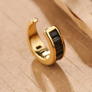 Macro shot of gold-plated C-shaped ear cuff featuring four inset black square zircons