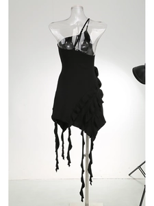 Detailed view of black dress with asymmetric hem, ruffle layers and long tassels