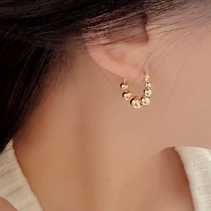 Élégantes boucles d'oreilles créoles perlées en argent S925 doré portées par un mannequin