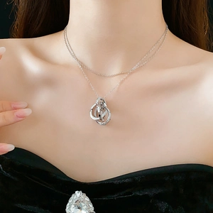Detail view of a silver double-layered necklace featuring interlocking geometric rings on a model