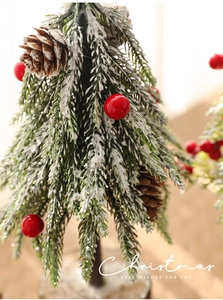 Close-up of a 24cm mini Christmas tree with snow-flocked needles, pine cones and berries
