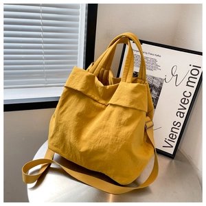 Detail of yellow nylon tote bag with pleated texture and adjustable strap on metal table