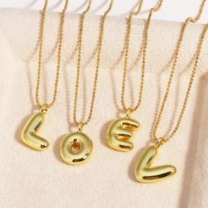 Gold-plated 3D bubble letter necklaces spelling LOVE on elegant beige velvet fabric