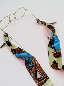 Detailed view of patterned silk ribbon strap on gold round glasses frames