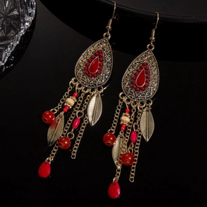 Boucles d'oreilles bohèmes vintage avec perles rouges et feuilles sur fond sombre poli