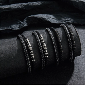 Close-up of triple layered black braided leather bracelets with metal beads on a stand