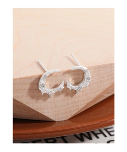 Macro view of silver crescent moon earrings with zircons and lava texture on wood