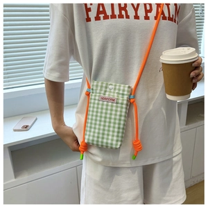 Green and white checkered mini crossbody bag with orange rope strap shown on a model