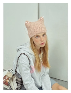 Detailed close-up of pink knit cat ear hat with delicate woven texture and ribbon bows