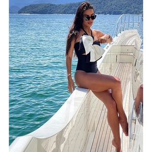 Detail of elegant one-piece swimsuit featuring a large white 3D bow on black bodice