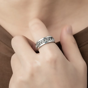 Close-up of a rotating silver titanium steel chain ring worn on a finger
