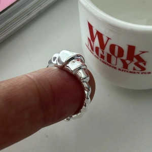 Macro detail of silver croissant ring showing twisted rope texture on a finger