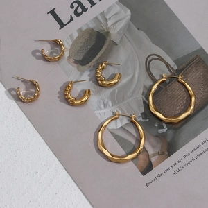 Three pairs of golden twisted hoop earrings on a magazine background for fashion styling