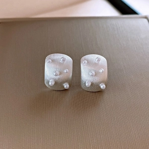 Detail of silver matte earrings with irregular squares and embedded white pearls