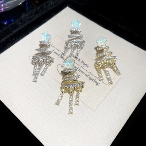 Macro detail of Christmas tree earrings with sparkling crystals in gold and silver finish