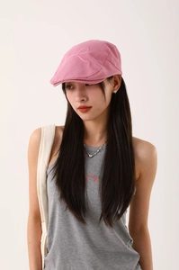 Gros plan d'une casquette plate rose avec nœud brodé sur tissu en coton doux