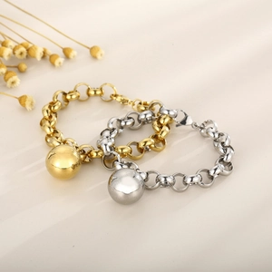 Polished gold and silver pearl chain bracelets with sphere pendants on white background