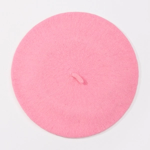 Close-up of pink wool knitted beret hat with small top tail detail on white background