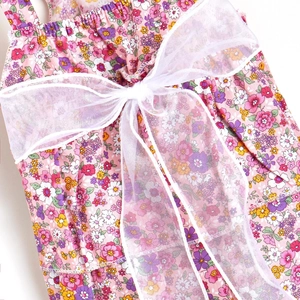 Detail of pink floral dog dress showing cotton fabric and a white mesh bow ornament