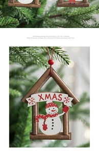 Detail of wooden snowman house ornament hanging on a Christmas tree with golden lights
