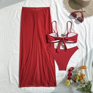 Flat lay of red three-piece bikini set with metal buckle, lace-up back and mesh sarong skirt