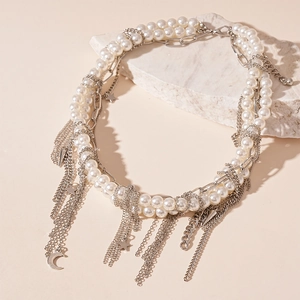 Detail of layered faux pearl necklace with silver tassels and moon star charms