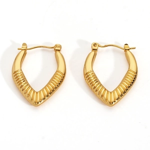 Macro shot of V-shaped gold hoop earrings featuring textured vertical stripes on a white base