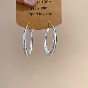 Détail de boucles d'oreilles pendantes rondes mates sur support en carton de marque