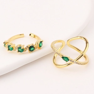 Detailed macro view of gold-plated adjustable rings with green emerald zircons on a tray