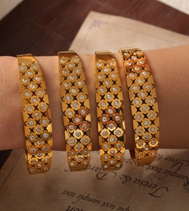 Detail of four-piece gold plated hollowed bracelets with floral lattice and small diamonds