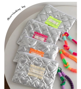 Top view of metallic silver quilted makeup bags with heart patterns and colorful handles
