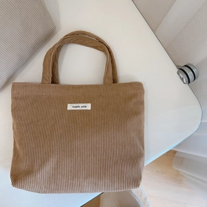 Detailed texture of brown corduroy tote bag with white woven simple wish label