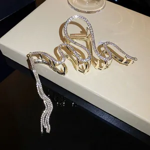 Close-up of golden snake claw clip with crystals and long hanging tassels detail