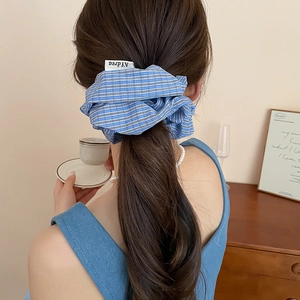 Blue plaid fabric scrunchie shown in a stylish ponytail on a female model