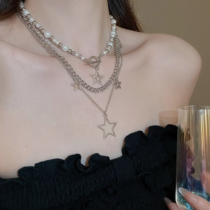 Detailed view of layered necklace set featuring star charms and pearl bead choker with OT clasp