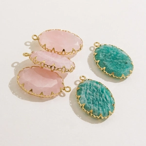 Oval natural stone pendants with faceted pink and teal crystals in gold-plated steel frames