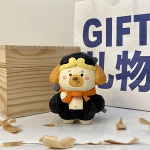 Close-up of a hand-carved style dog figurine wearing a yellow pilot hat and orange scarf