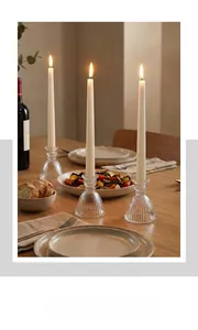 Close-up of a clear glass pleated skirt candle holder with long white taper candle