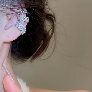 Detail of silver-colored zirconia ear cuffs set worn on ear bone for non-pierced ears