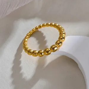 Minimalist gold beaded titanium steel ring for women displayed on a white artistic pedestal