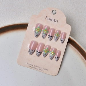 Close-up of almond fake nails featuring zebra stripes and 3D floral accents with crystals