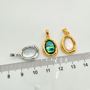 Macro shot of oval shell pendants with scale ruler showing 2.2cm height and 1.6cm width