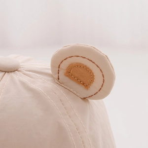 Detailed close-up of cute bear ears and stitching on breathable baby sun hat fabric