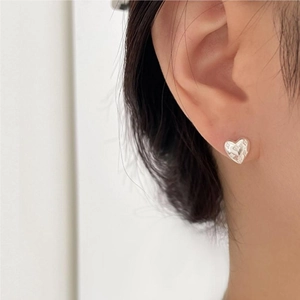 Close-up of minimalist heart-shaped silver stud earring worn on model's earlobe