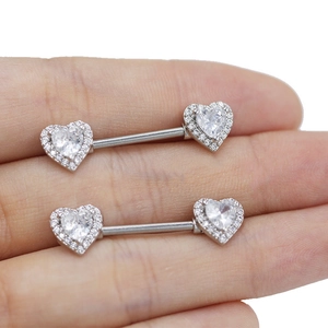 Close-up of heart-shaped silver nipple rings with sparkling zircon inlay held by hand