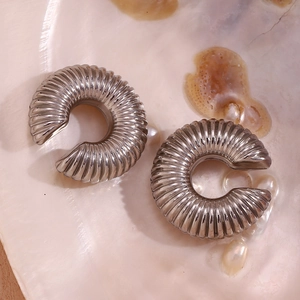 Detailed macro view of silver spiral textured ear cuffs on a mother-of-pearl shell