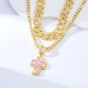 Sparkling gold Cuban link and tennis chain with pink cross pendant in starburst lighting